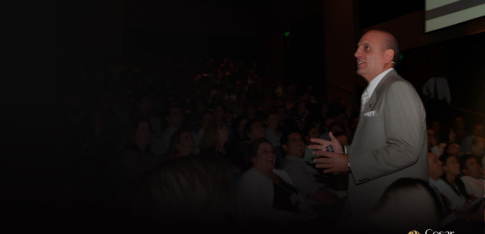 Cesar Romão conduzindo uma palestra para um auditório lotado
